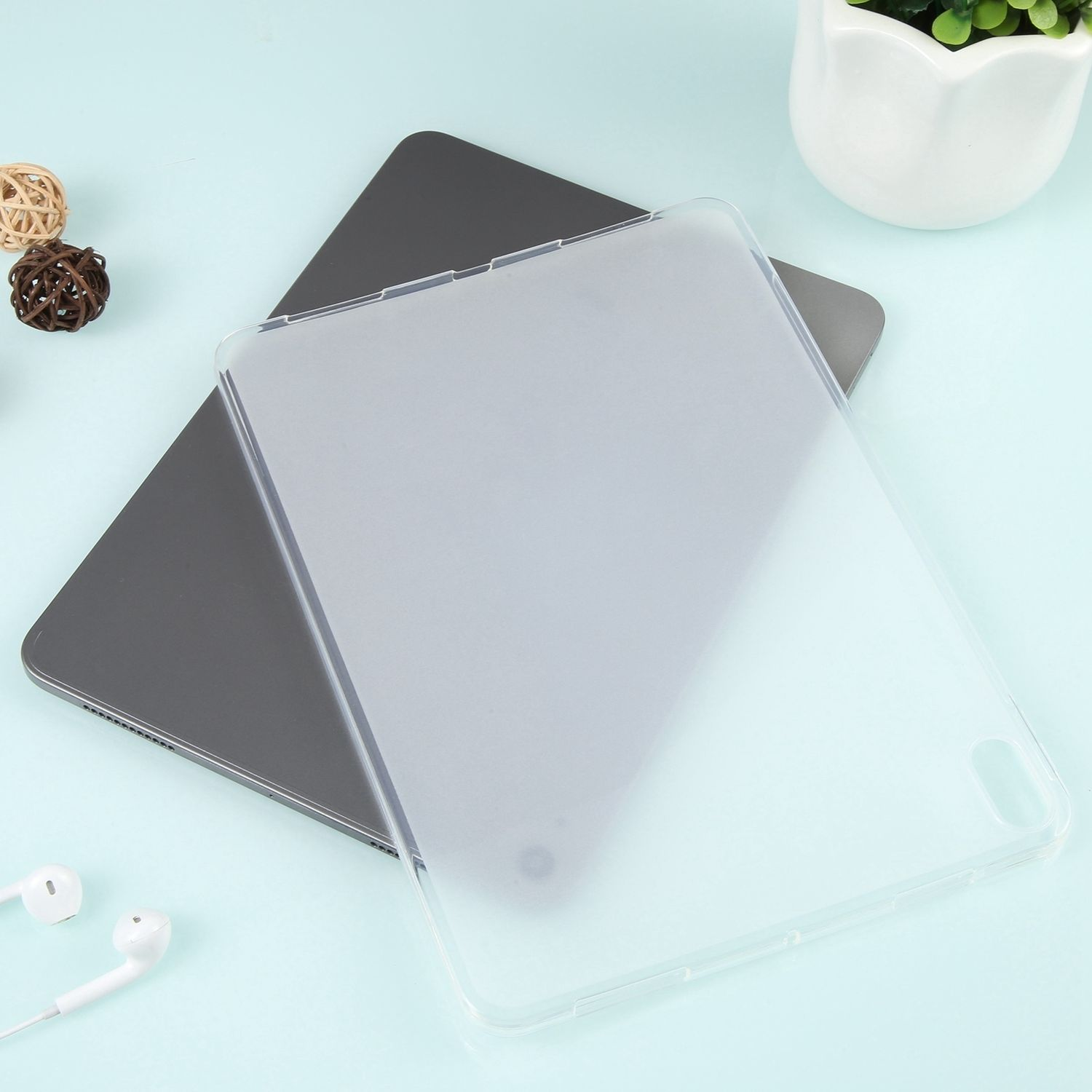 Transparente Tablethülle auf einem Tablet. Weiße Ohrhörer links. Blauer Hintergrund.