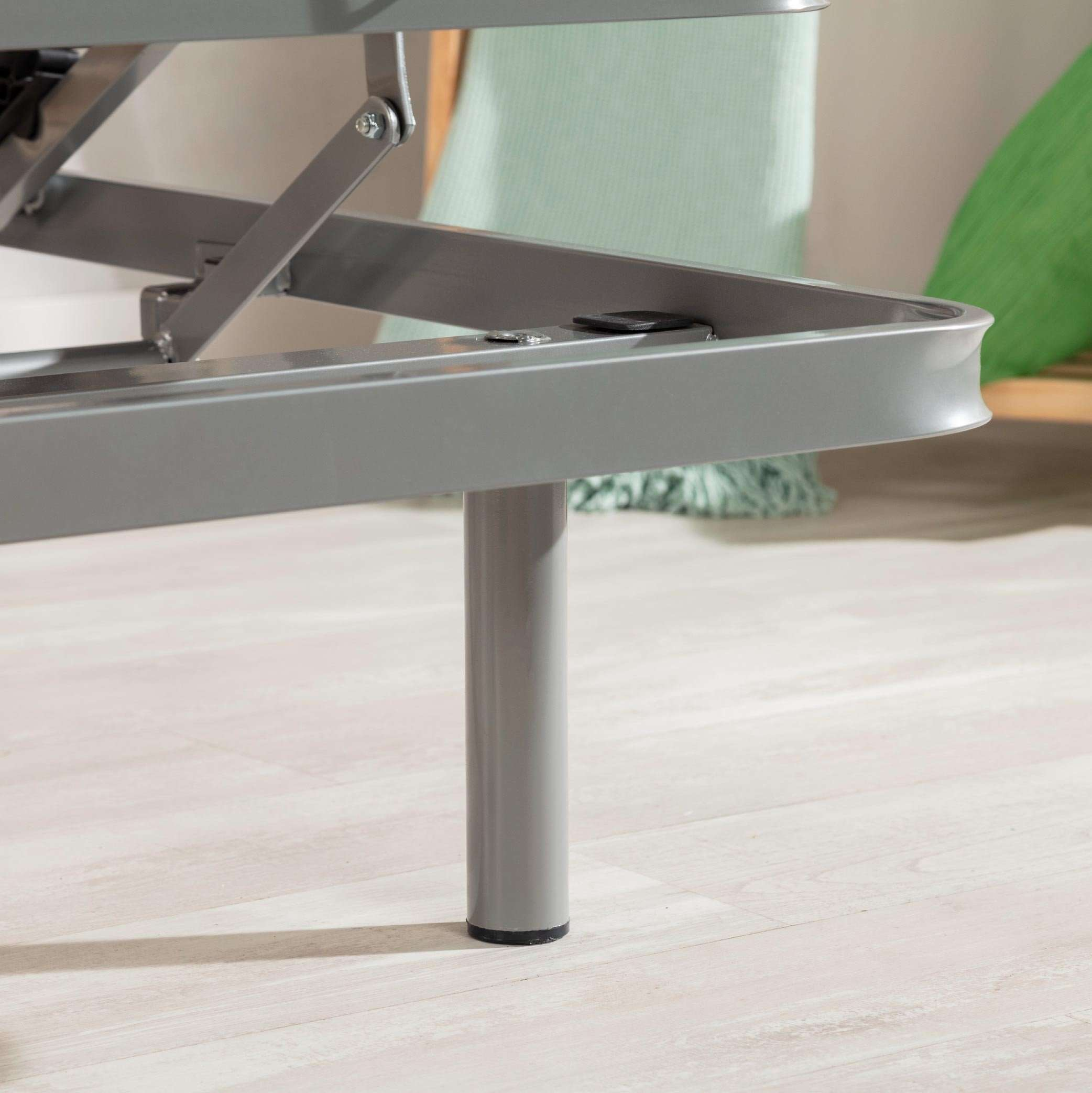 Estructura de cama gris con suelo de madera clara, manta menta y fondo borroso.