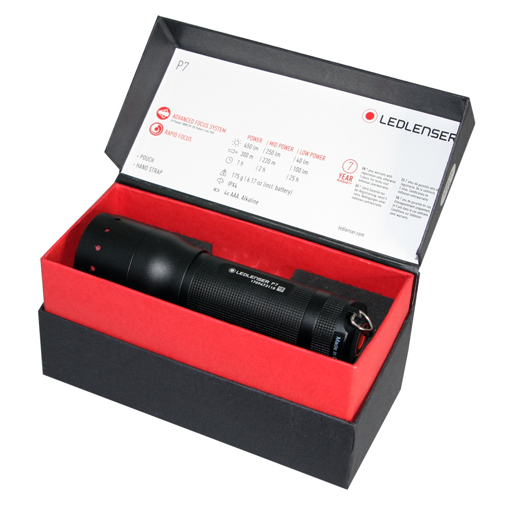 Czarna latarka w pudełku, z tekstem o jej funkcjach. Czerwone wnętrze.