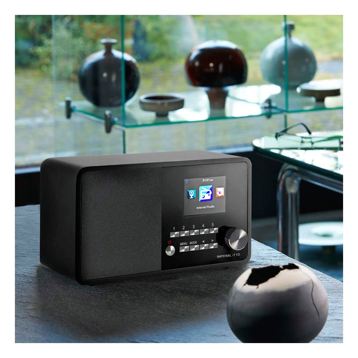 Radio numérique noire avec écran, boutons et vase noir.