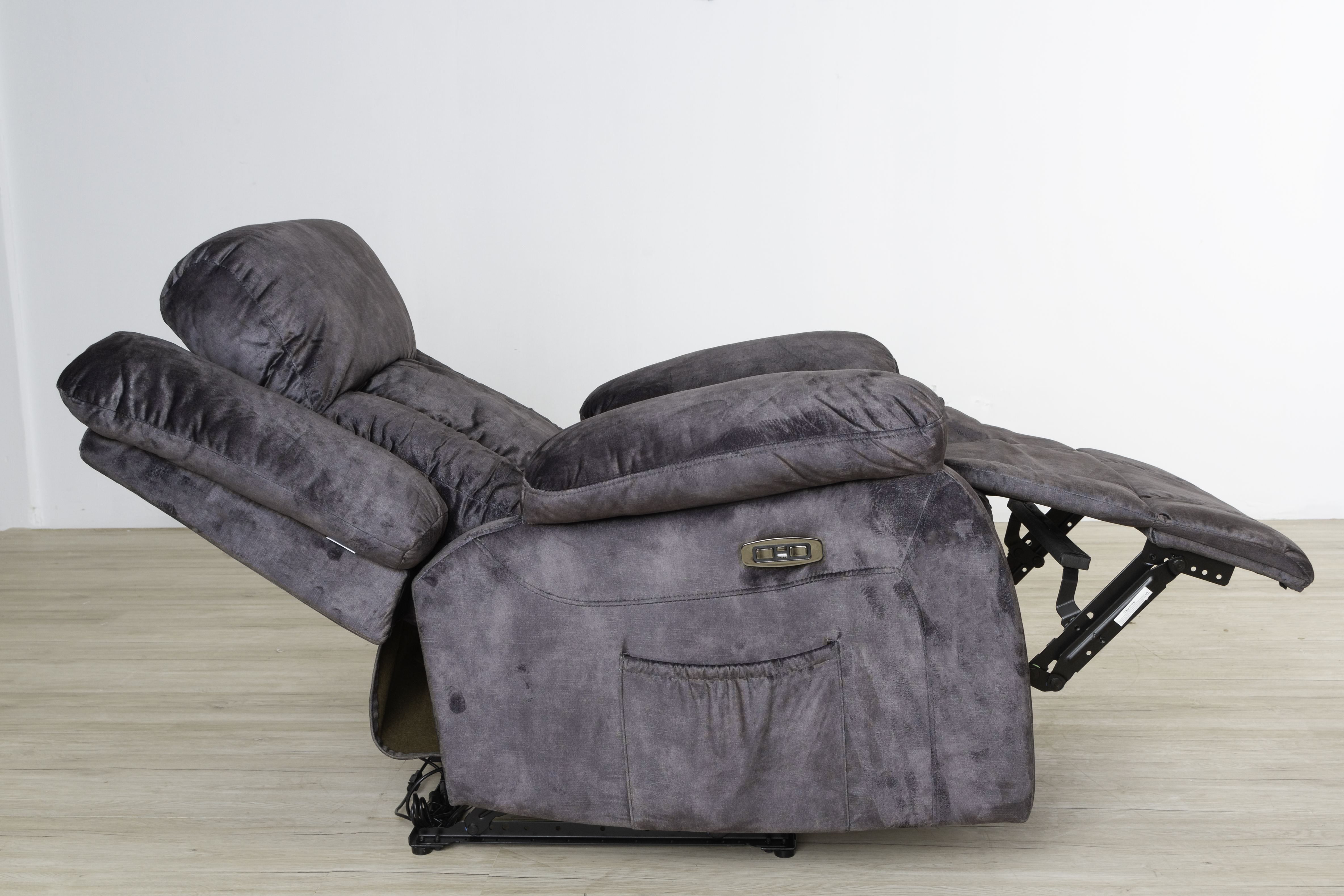 Sillón reclinable gris totalmente reclinado. La silla está en un suelo de madera, fondo blanco.