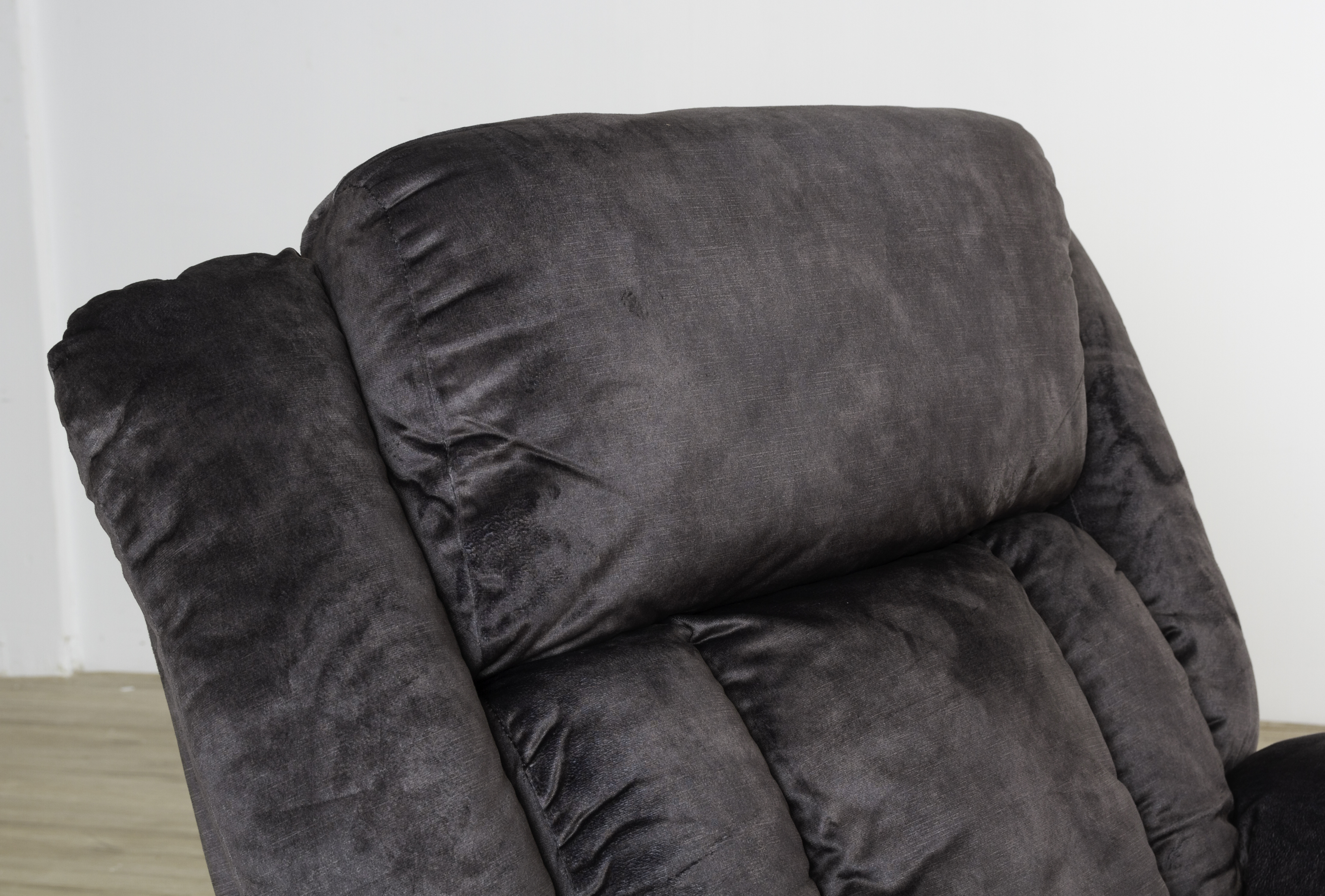 Primer plano del reposacabezas de un sillón reclinable, tela gris oscuro.