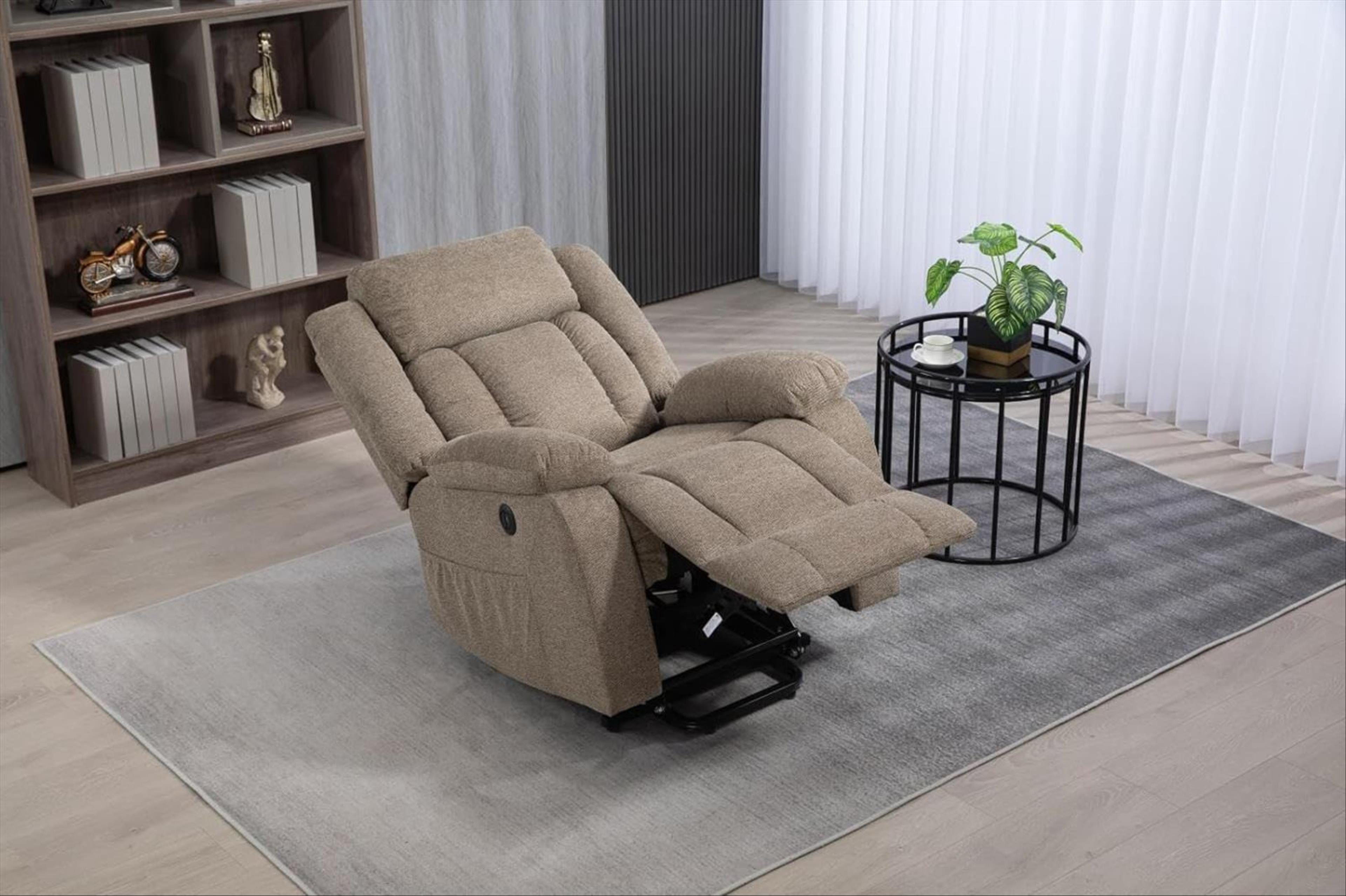 Sillón reclinable beige con reposapiés extendido, sobre una alfombra gris con mesa auxiliar y planta.