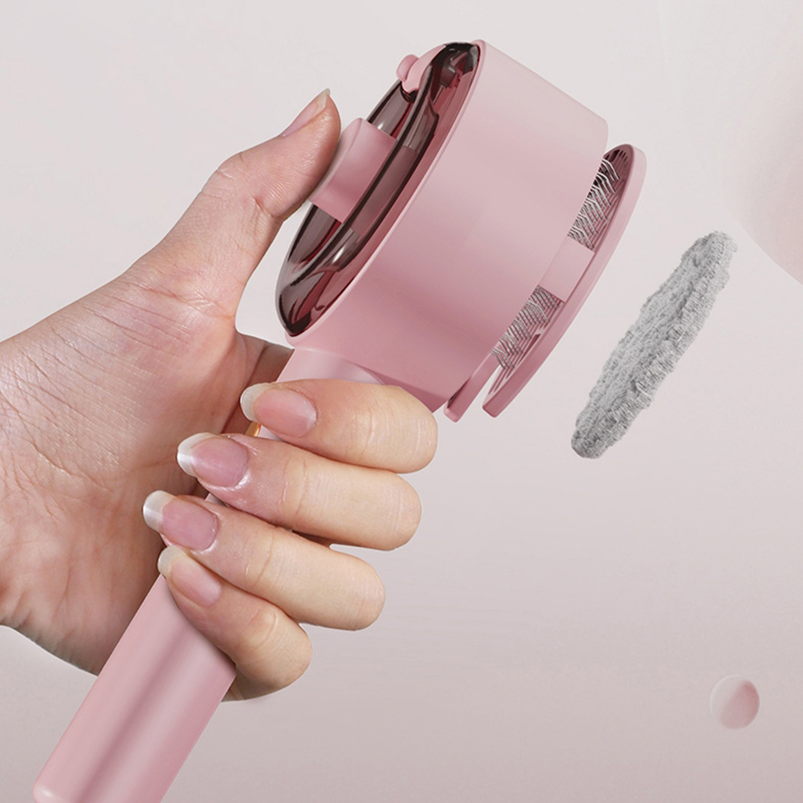 Rosa Tierhaarentferner-Bürste in einer Hand mit grauem Reinigungspad.