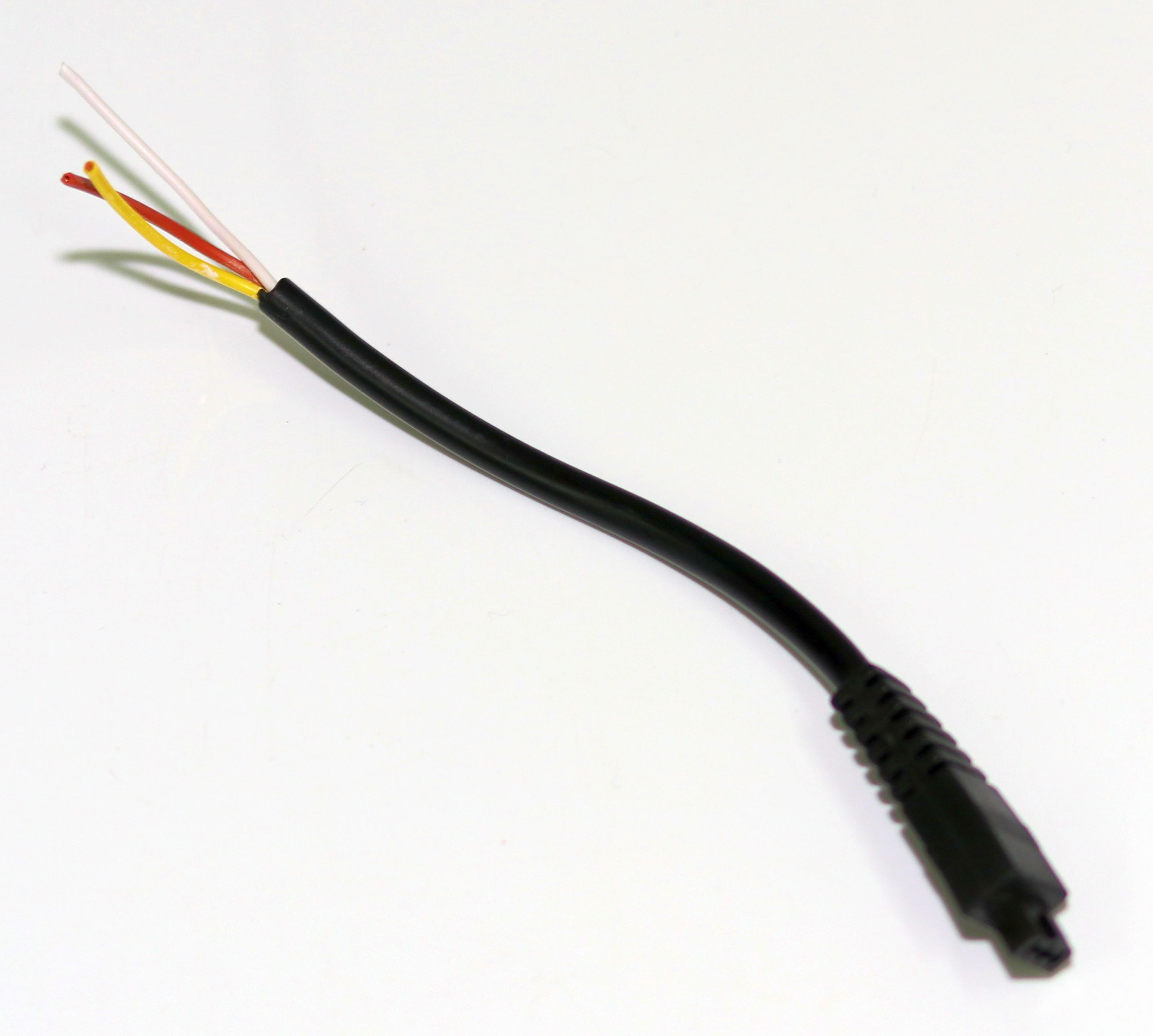 Schwarzes Kabel mit drei freiliegenden Drähten: rot, gelb und weiß. Das Kabel liegt auf Weiß.