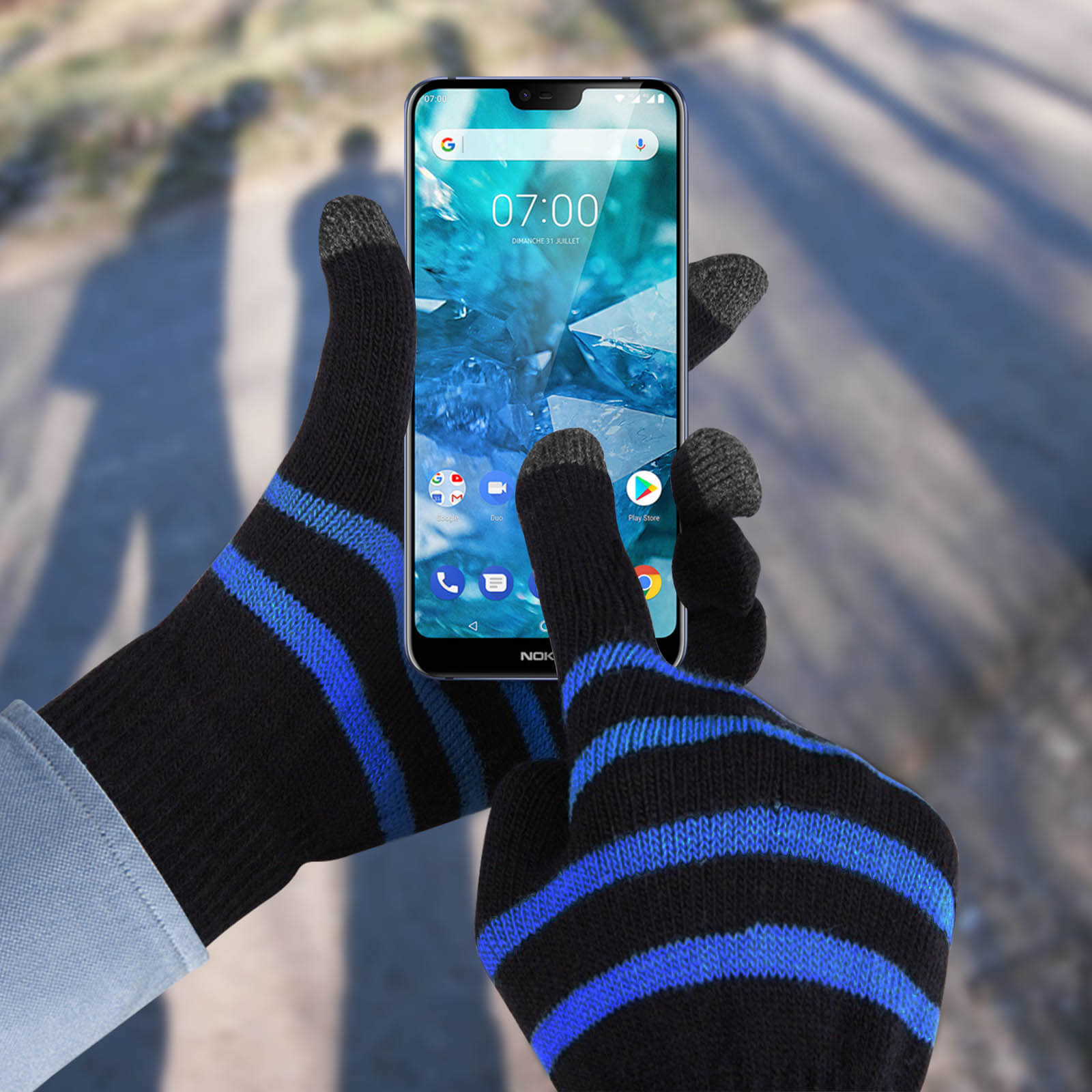 Mani con guanti a righe nere e blu toccano uno schermo di telefono con un'interfaccia.