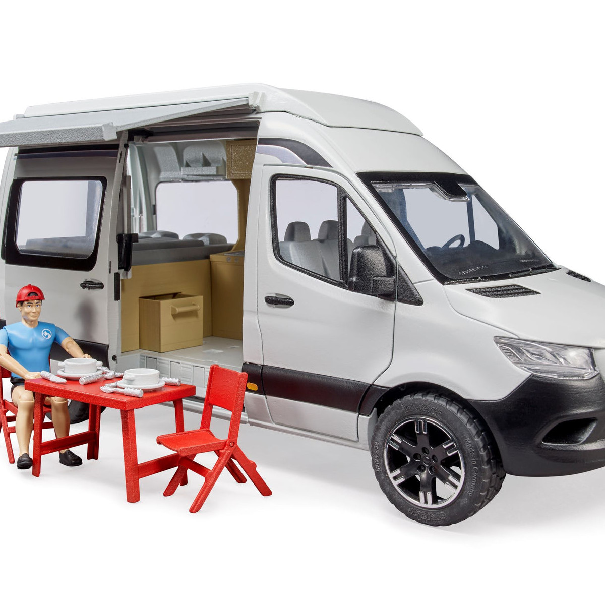 Pokazano zabawkę w postaci kampera z mężczyzną i ustawionym stołem. Mężczyzna siedzi, a na stole są talerze.