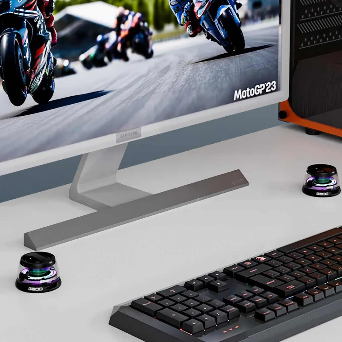 Configuración de juego con monitor, teclado y dos gadgets de escritorio iluminados y coloridos.