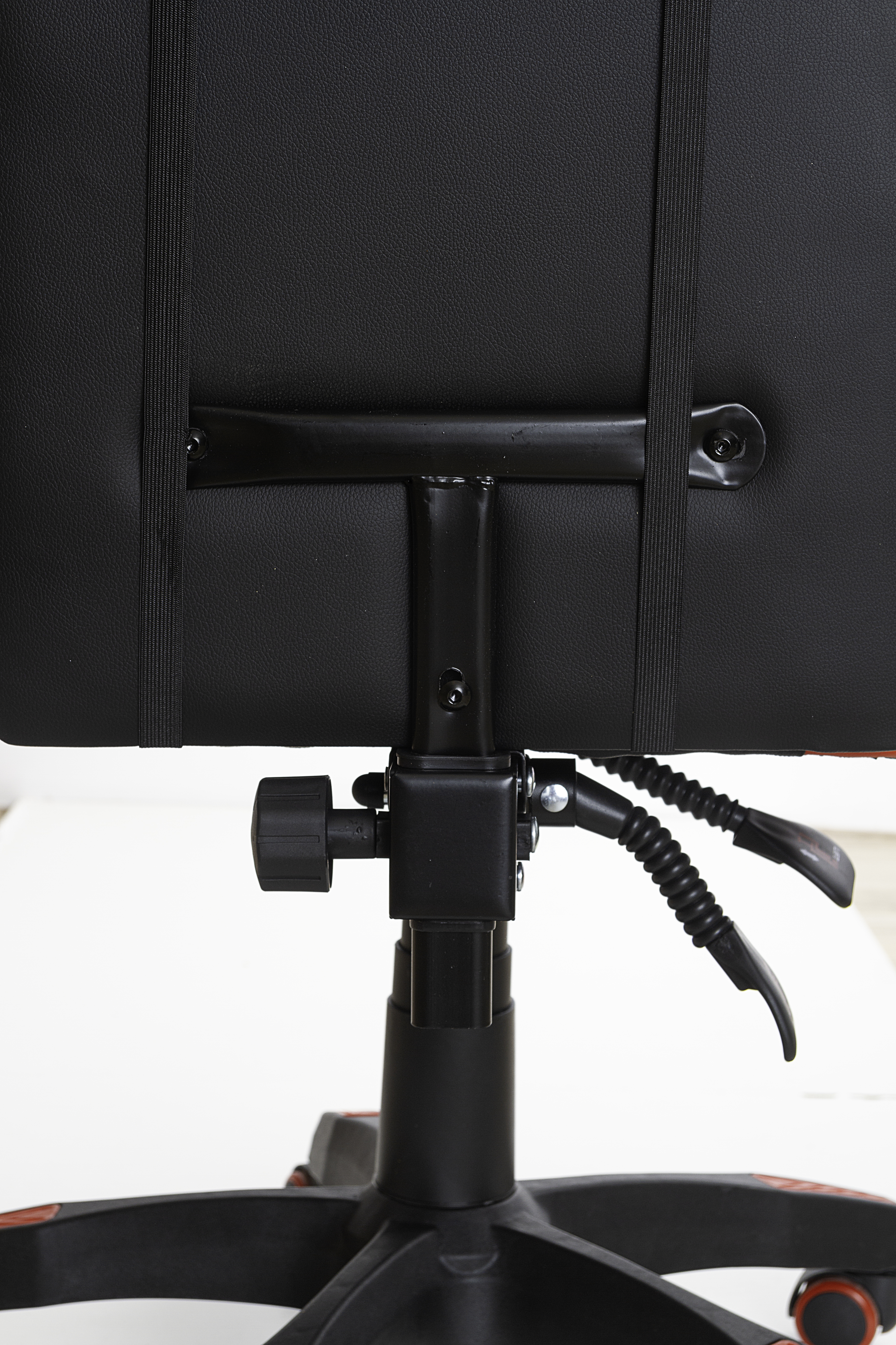 Parte trasera de una silla gaming negra y roja, mostrando el soporte lumbar y el mecanismo de ajuste.