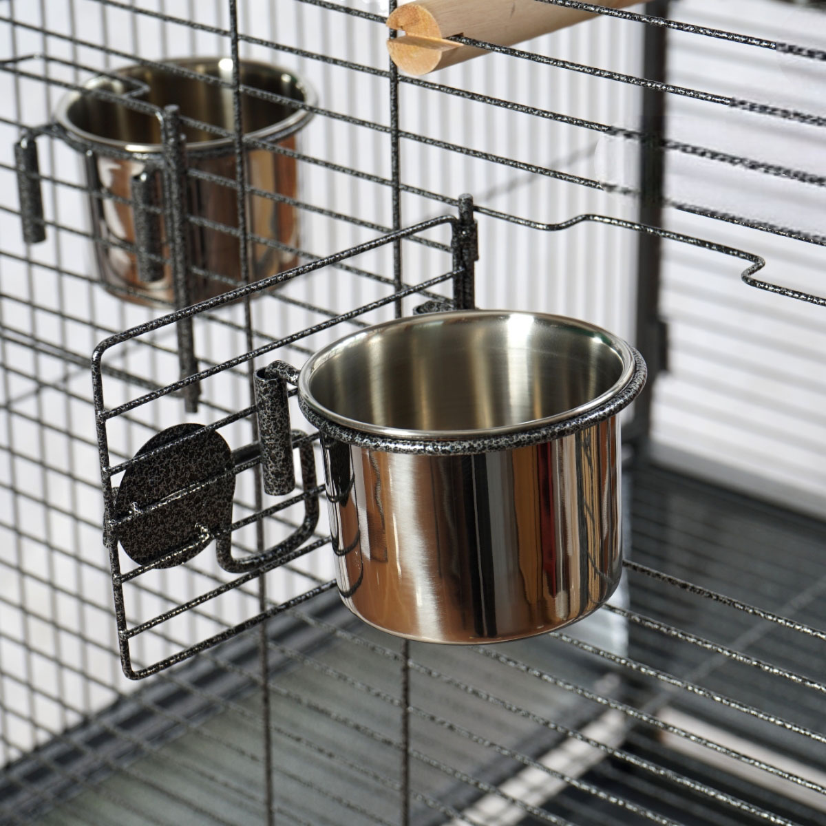 Zwei Metallschalen an einem Metallkäfig befestigt. Schalen sind silber und glänzend.
