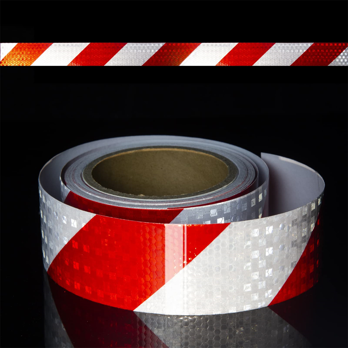 Eine Rolle reflektierendes Klebeband mit rot-weißen Diagonalstreifen. Das Band liegt auf schwarzem Grund.
