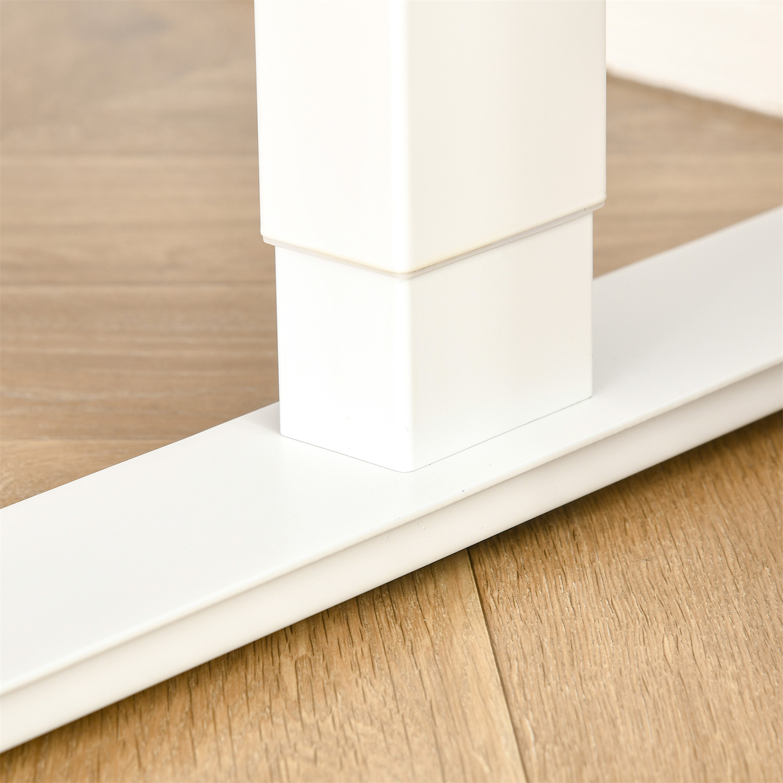 Weißes Schreibtischbein. Das Bein ist quadratisch und steht auf einem Holzboden. Der Boden ist hellbraun.