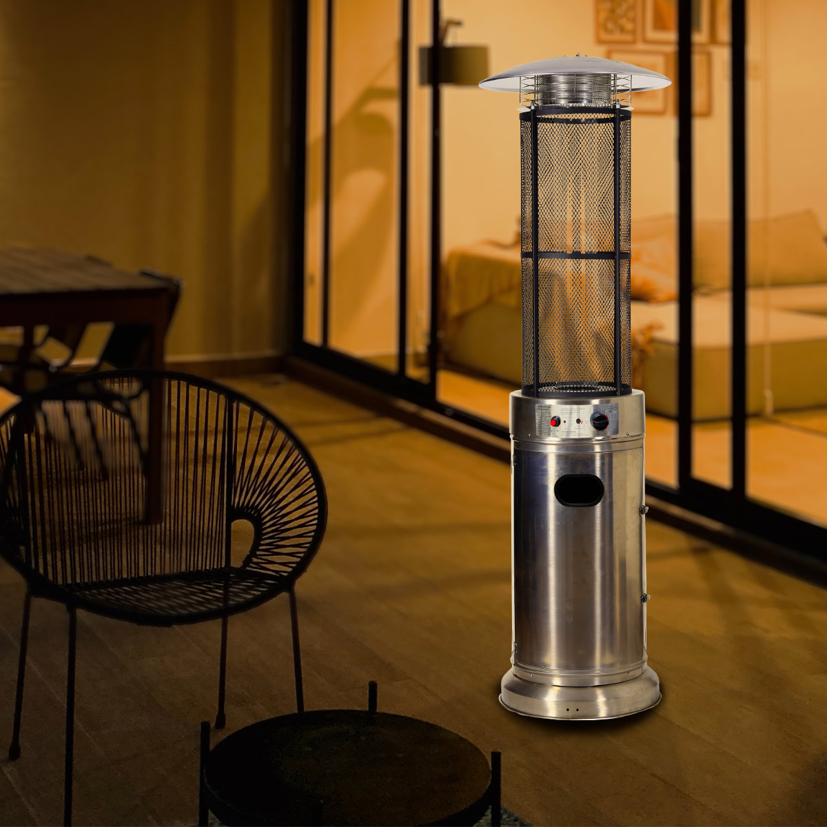Srebrna nagrzewnica tarasowa z czarną siatką, obok czarnego krzesła i stołu.