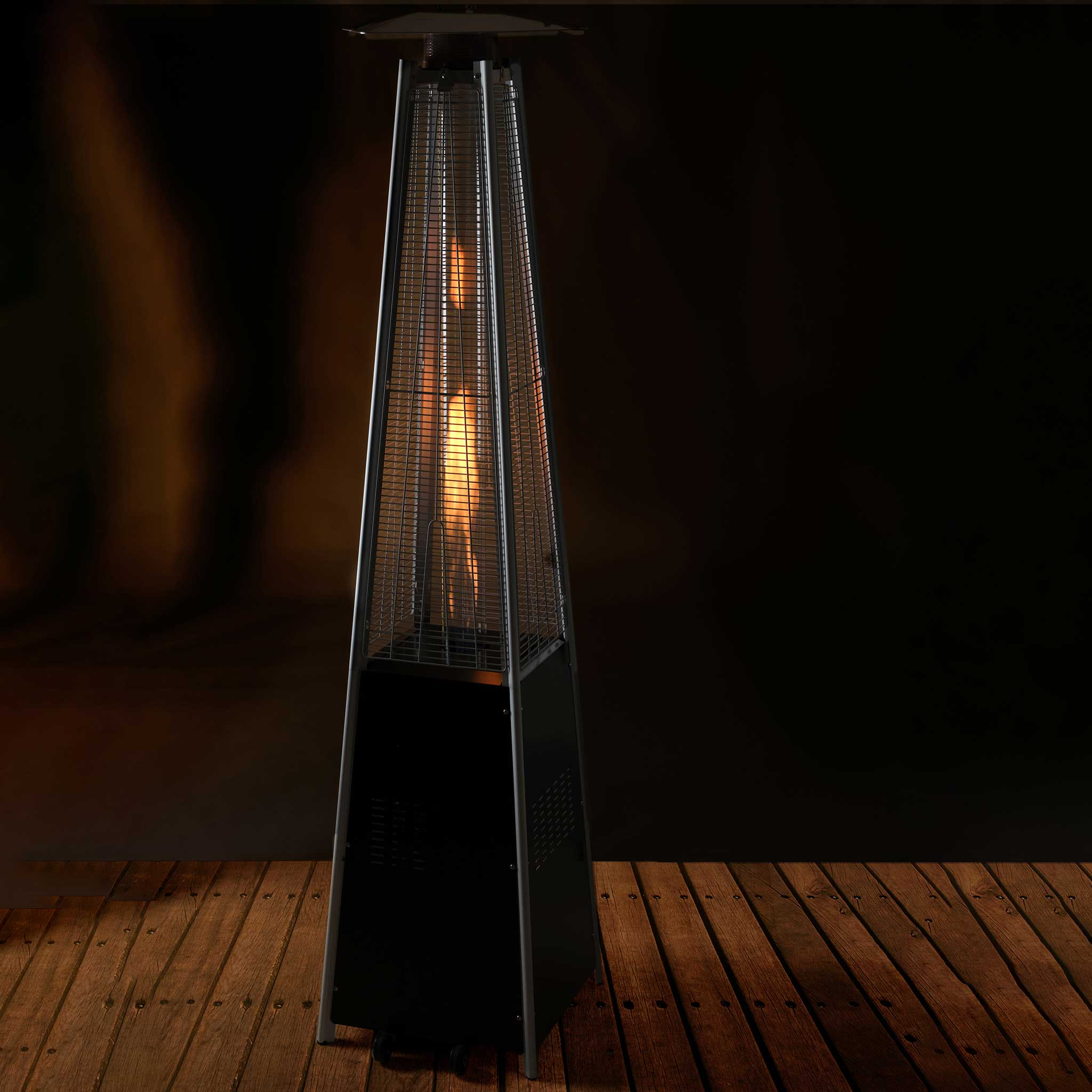 Czarny grzejnik zewnętrzny z płomieniem w środku. Znajduje się na drewnianym tarasie. Tło jest ciemne.