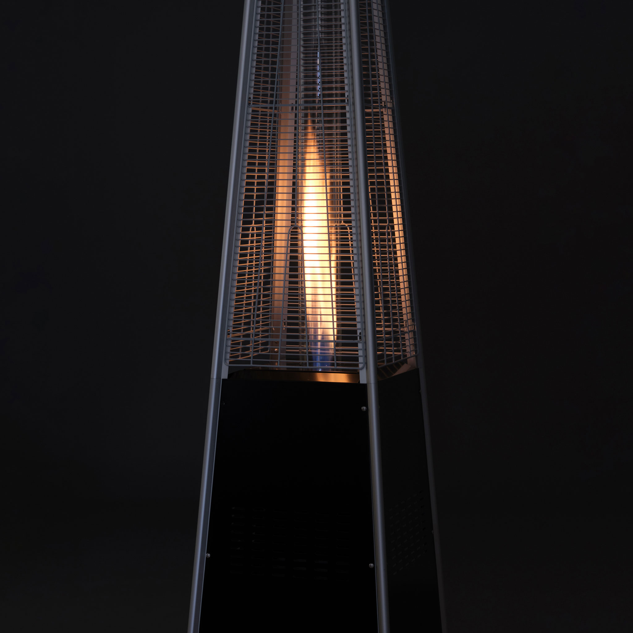 Wieżowy grzejnik gazowy z ogniem, czarny i srebrny metal, ciemne tło.