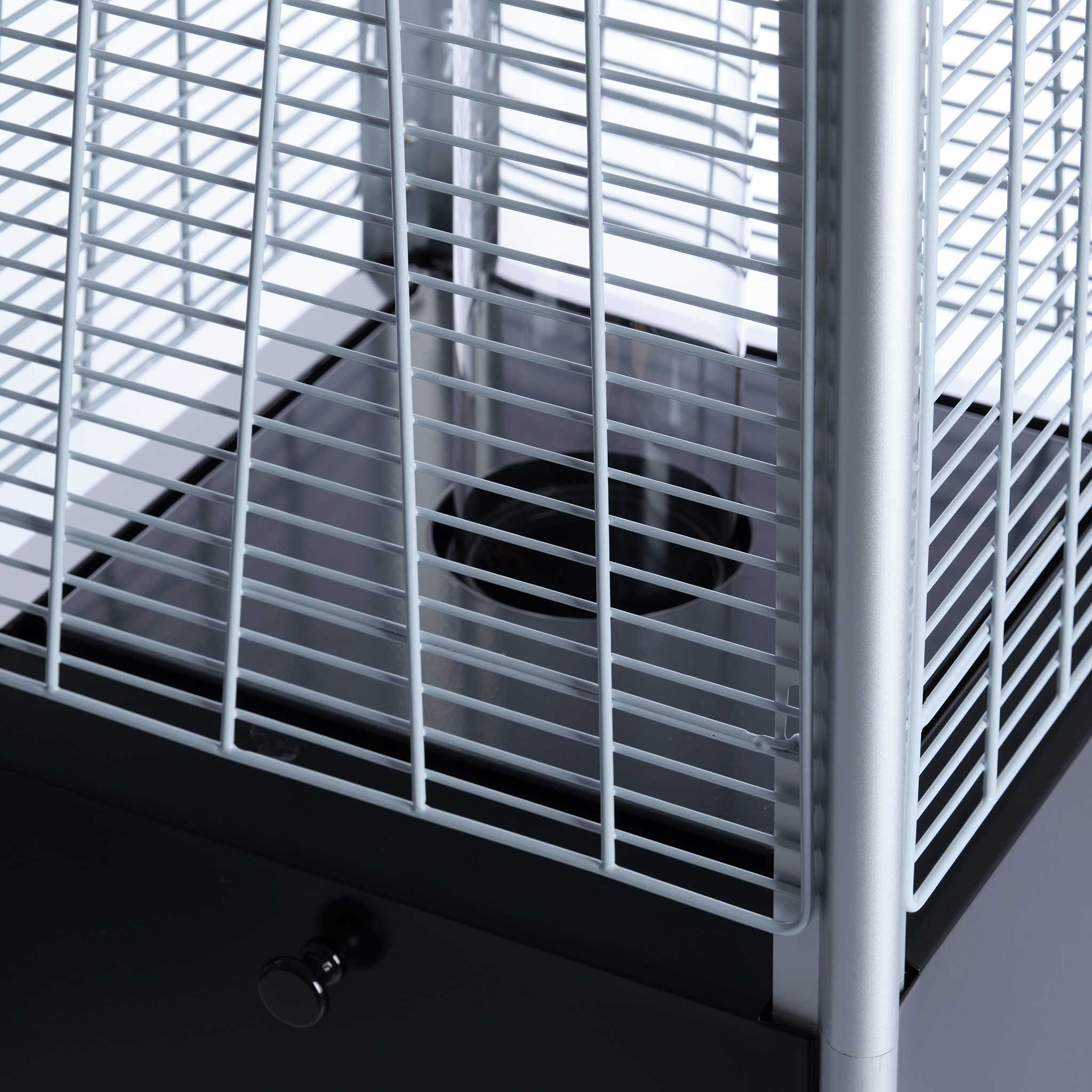 Zbliżenie metalowej klatki ochronnej grzejnika zewnętrznego. Czarna podstawa i pokrętło regulacji widoczne.