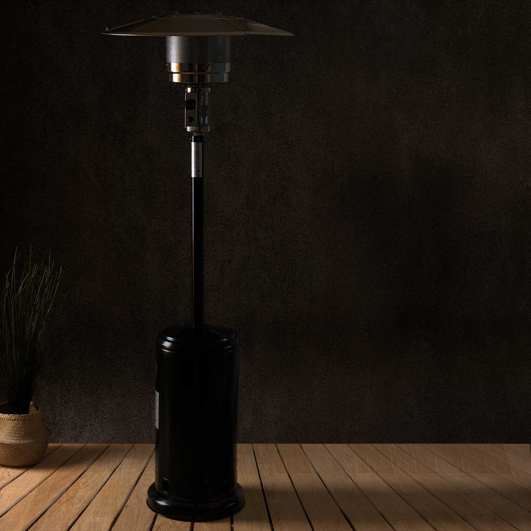 Czarny grzejnik tarasowy na zewnątrz z okrągłym blatem i wysokim, cylindrycznym korpusem.