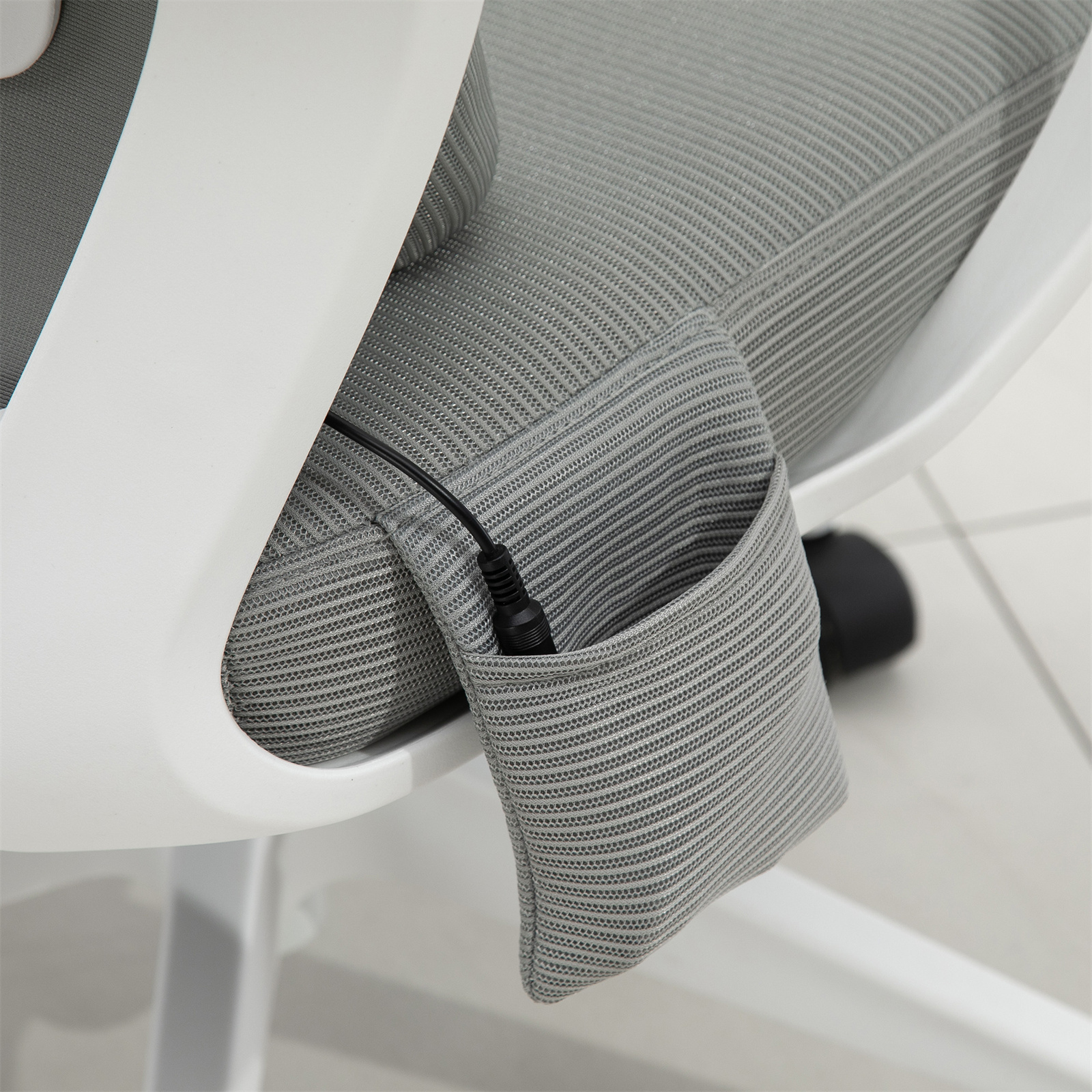 Nahaufnahme eines grauen Kissens eines weißen Stuhls mit einer Tasche, die ein schwarzes Kabel hält.