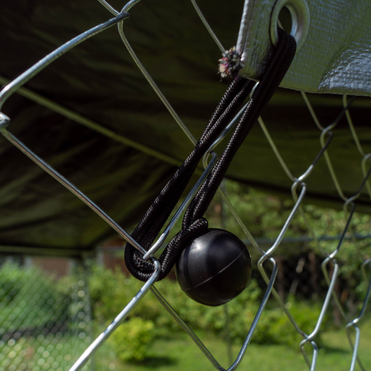Schwarzer Ball hängt in einem Maschendrahtzaun. Dunkler Hintergrund.