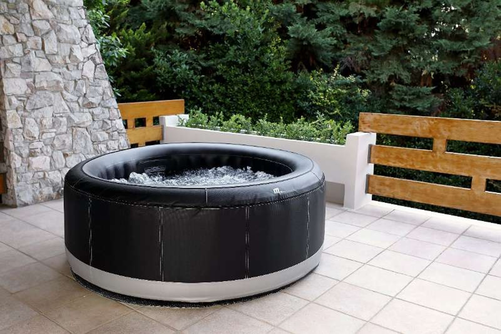 Schwarzer aufblasbarer Whirlpool im Freien, mit weiß-grauem Sockel, auf einer Terrasse.