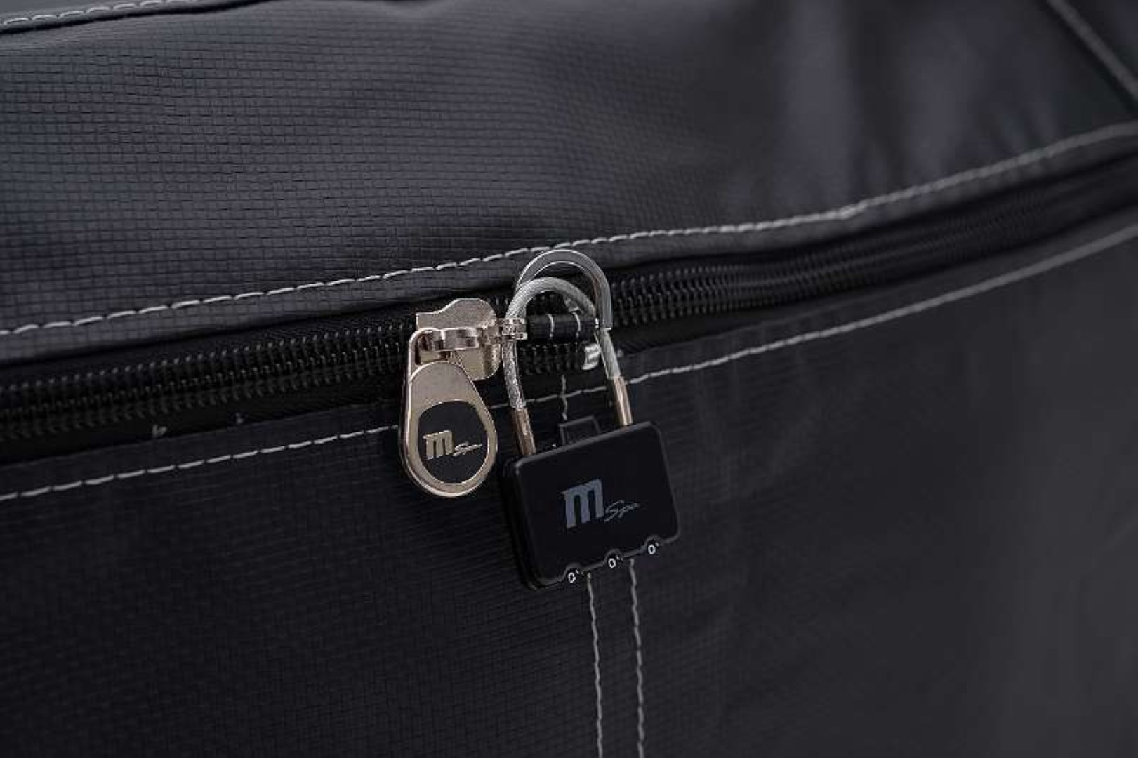 Eine schwarze Reisetasche mit Zahlenschloss. Der Reißverschluss ist sichtbar.