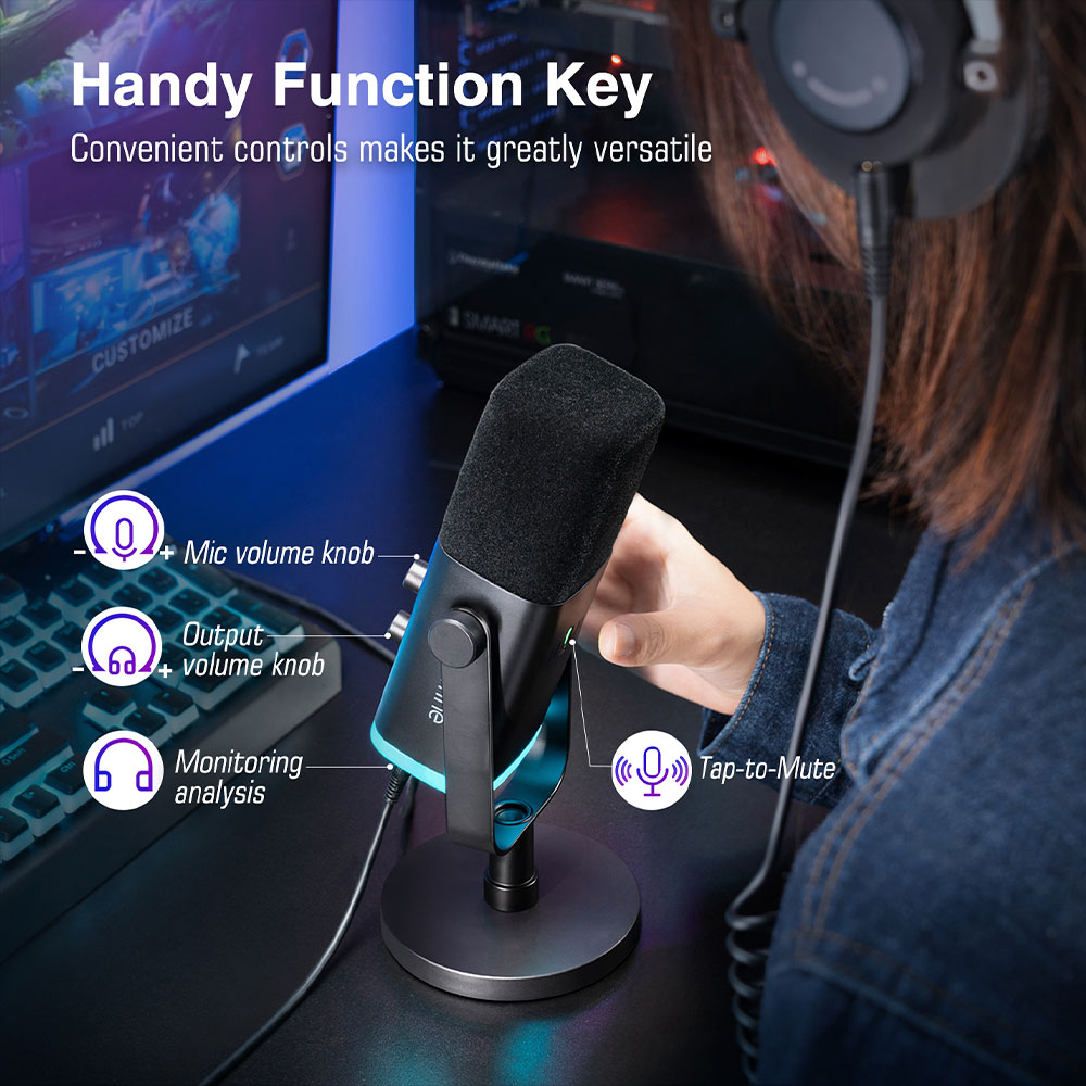 Une personne utilise un microphone noir avec des accents bleus et trois boutons de commande. Un moniteur et un casque sont visibles.