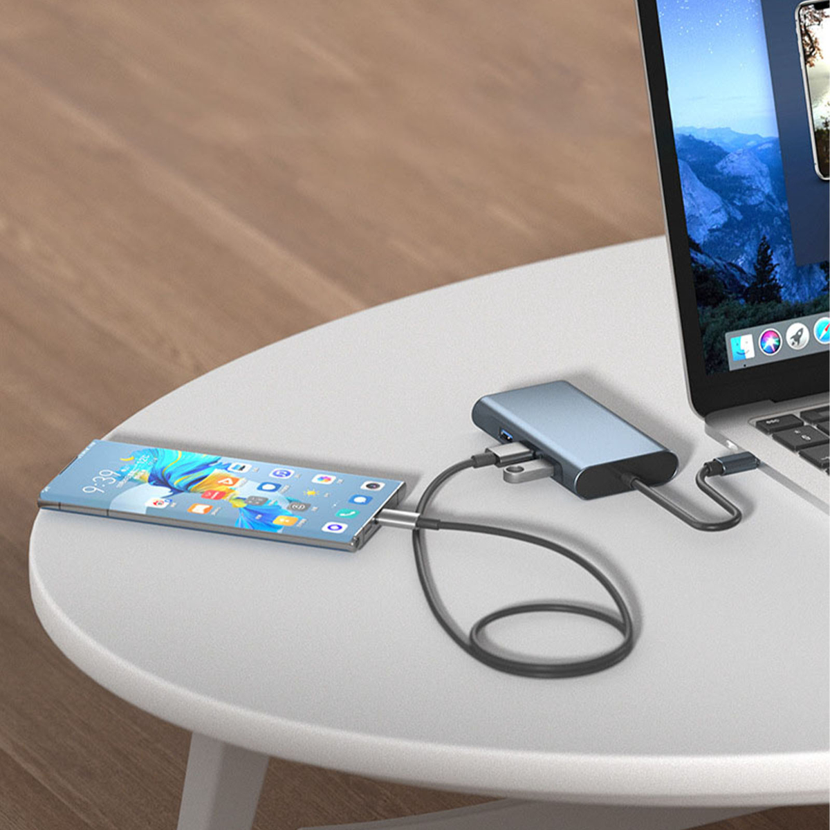 Telefon mit Hub und Laptop auf weißem Tisch verbunden.