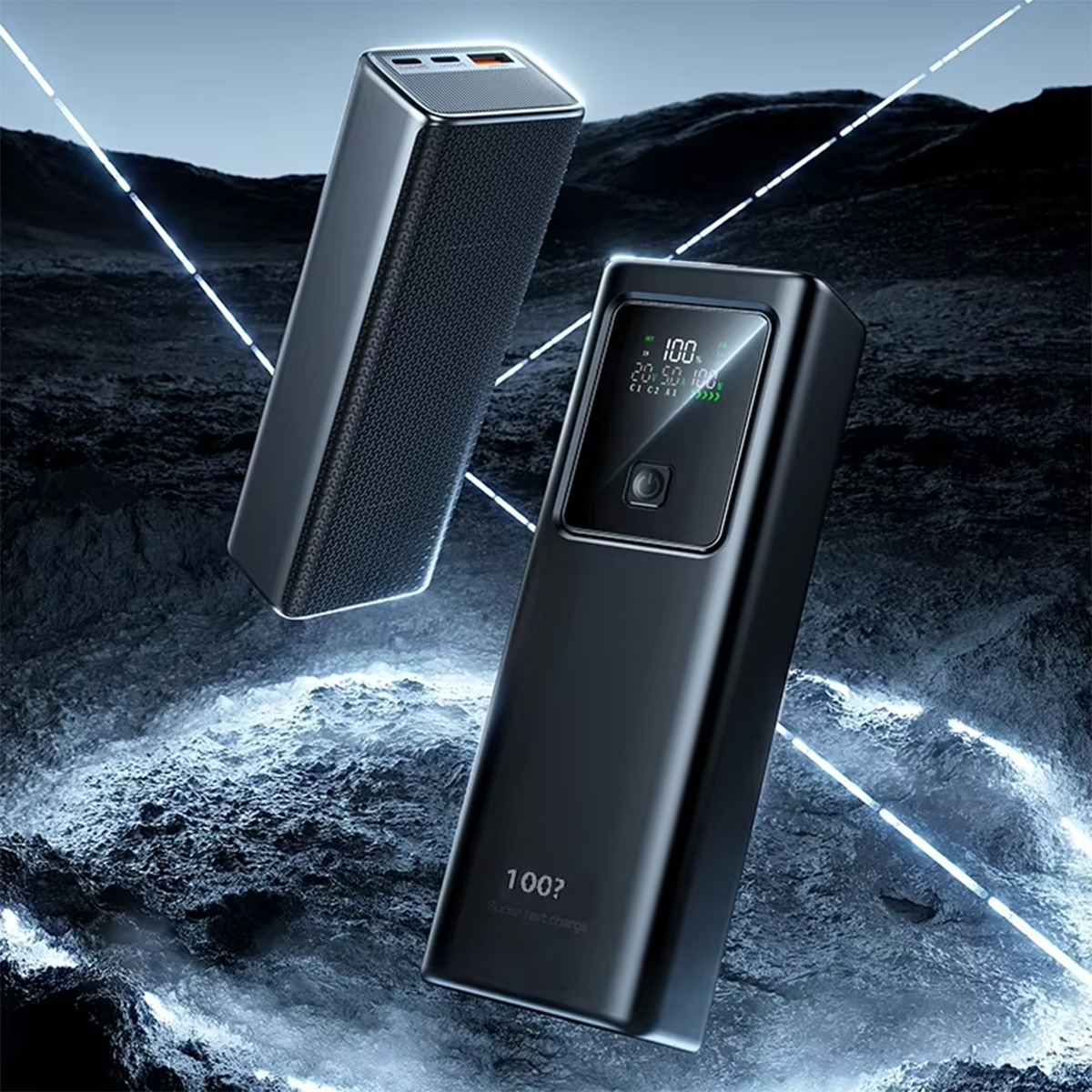 Dos power banks negros sobre una superficie rocosa. Uno tiene una pantalla, el otro una superficie texturizada.