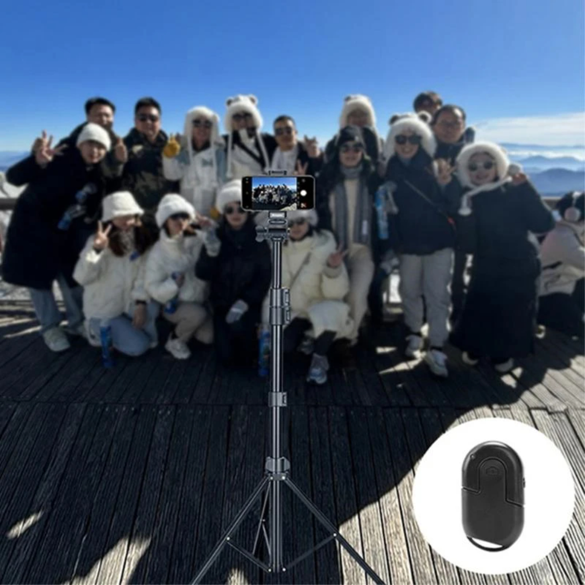 Un grupo de personas posando con un smartphone en un trípode para una foto, mando a distancia en la mano.