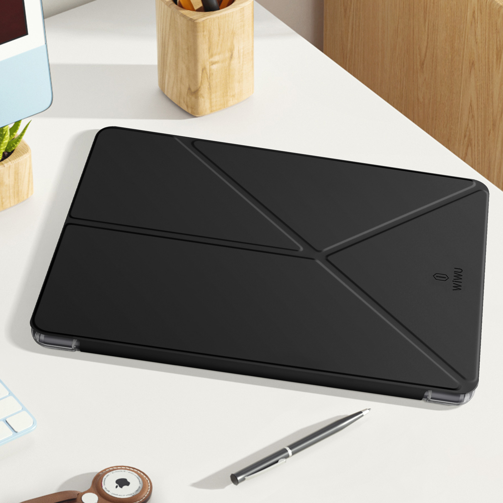 Custodia nera per tablet su una scrivania bianca. Una penna e altri oggetti sono visibili.