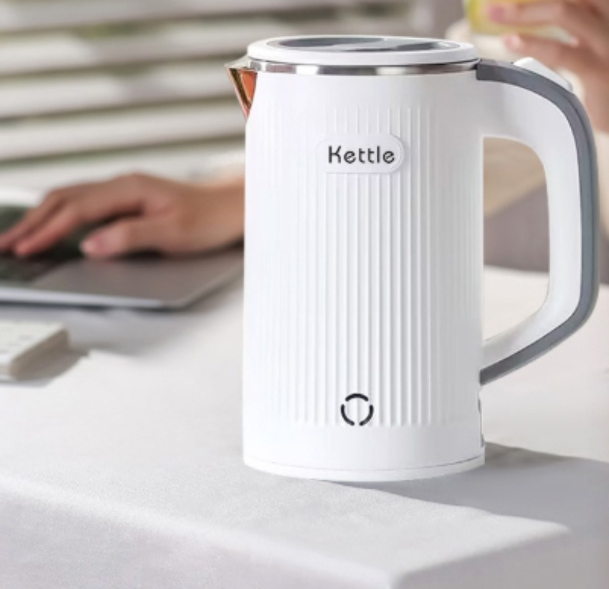 Ein weißer Wasserkocher mit Griff und dem Wort 'Kettle' auf der Vorderseite.