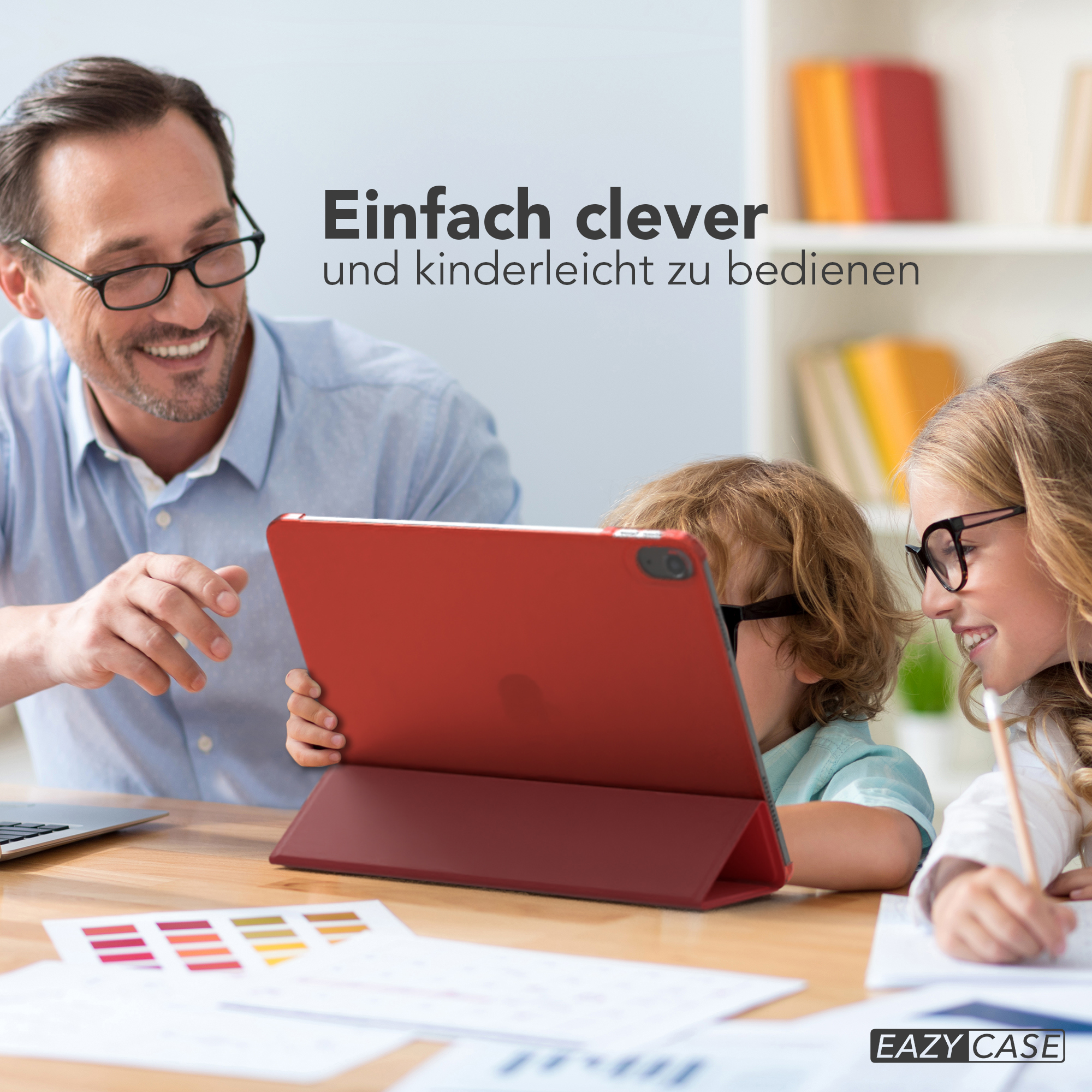 Mann und Kinder betrachten rotes Tablet mit roter Hülle, in hellem Raum.