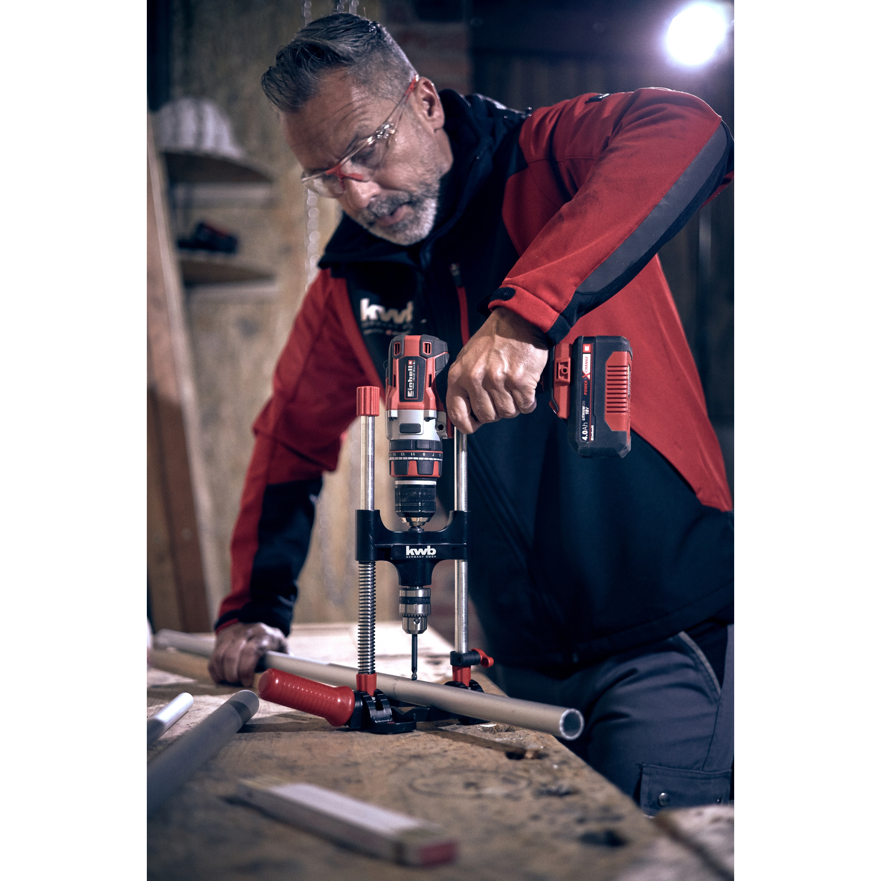 Eine Person benutzt einen Bohrer auf Holz. Sie arbeiten in einer Werkstatt.