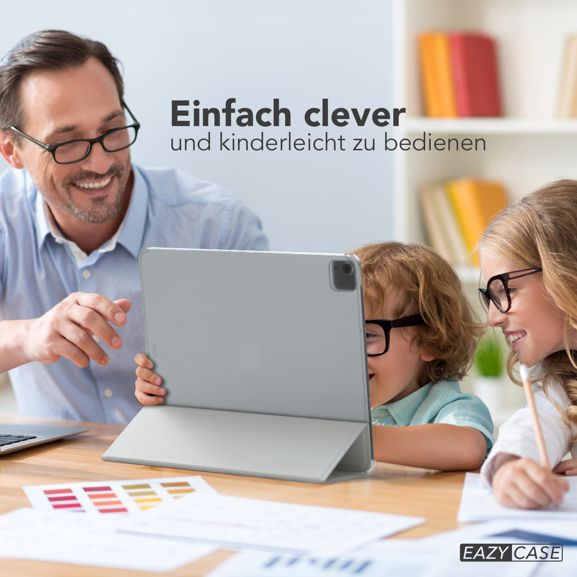 Vater und Kinder schauen auf ein Tablet. Das Tablet liegt auf einem Tisch mit Farbmustern.