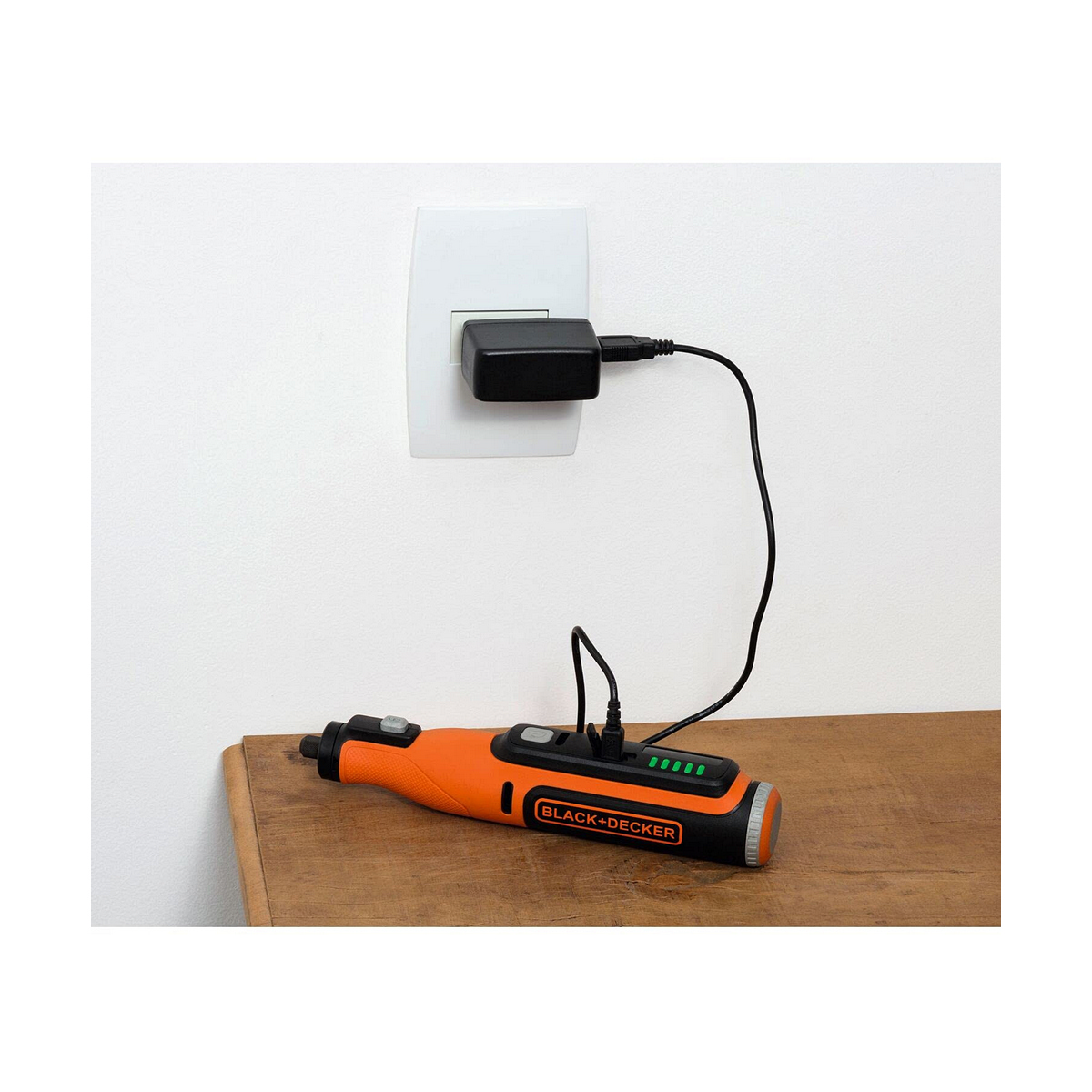 Orangener und schwarzer Bohrer mit einem schwarzen Ladekabel, das in eine Steckdose eingesteckt ist.