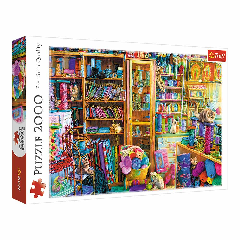 Pudełko z puzzlami z kotami i materiałami do szycia. Koty siedzą wokół półek wypełnionych tkaniną i przędzą.