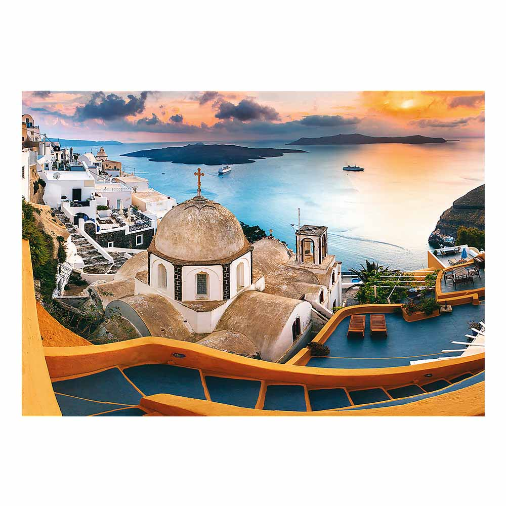 Zdjęcie Santorini, Grecja. Białe budynki, błękitna woda i kościół z kopułą o zachodzie słońca.