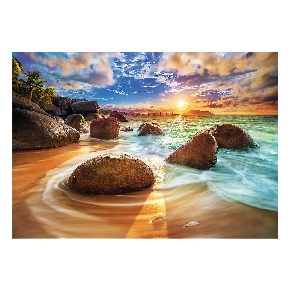 Strandszene mit Felsen, Wellen und Sonnenuntergang. Der Himmel ist blau mit Wolken.