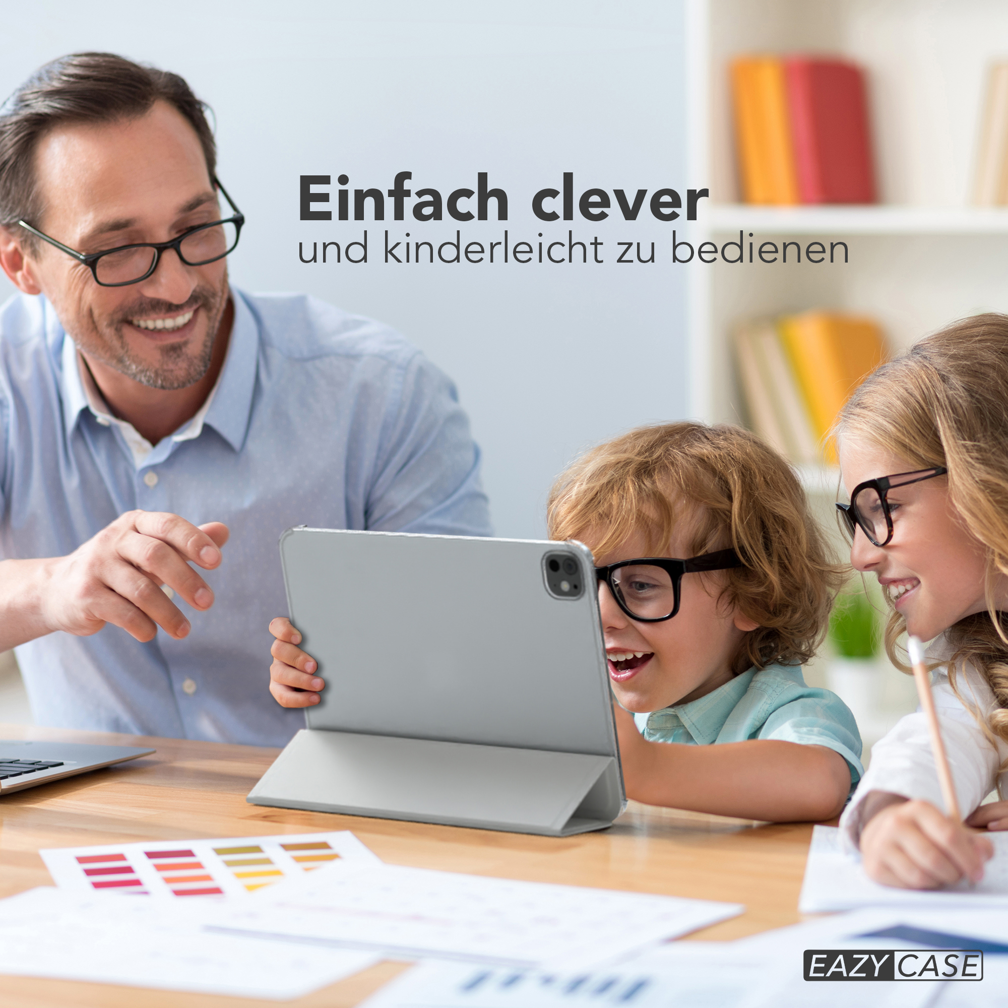 Ein Vater und zwei Kinder schauen auf ein Tablet. Die Kinder tragen Brillen, das Tablet wird hochgehalten.