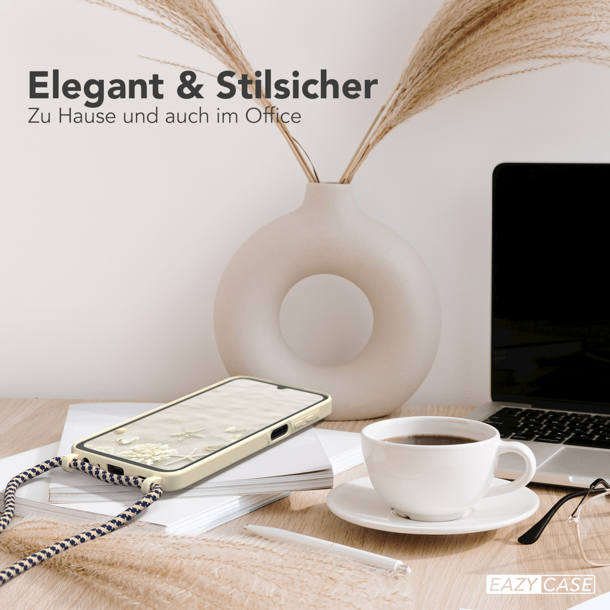 Ein Telefon und eine Tasse Kaffee auf einem Tisch neben einem Laptop und einer Vase mit Pflanzen.