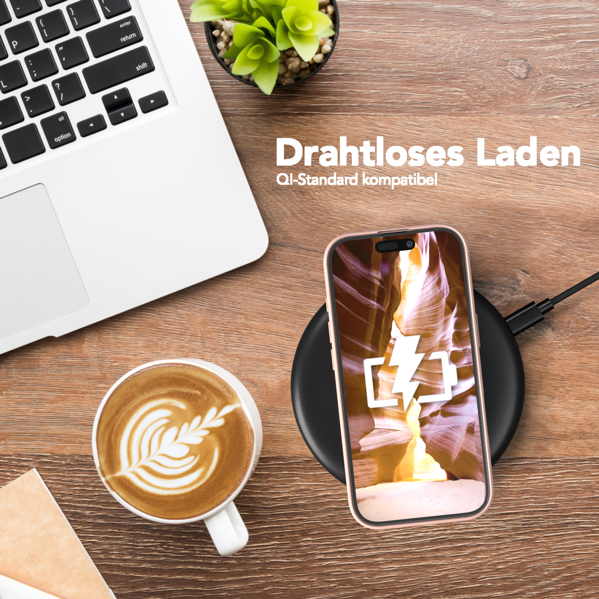 Ein Telefon, das drahtlos auf einem Pad geladen wird, neben Kaffee und einem Laptop.