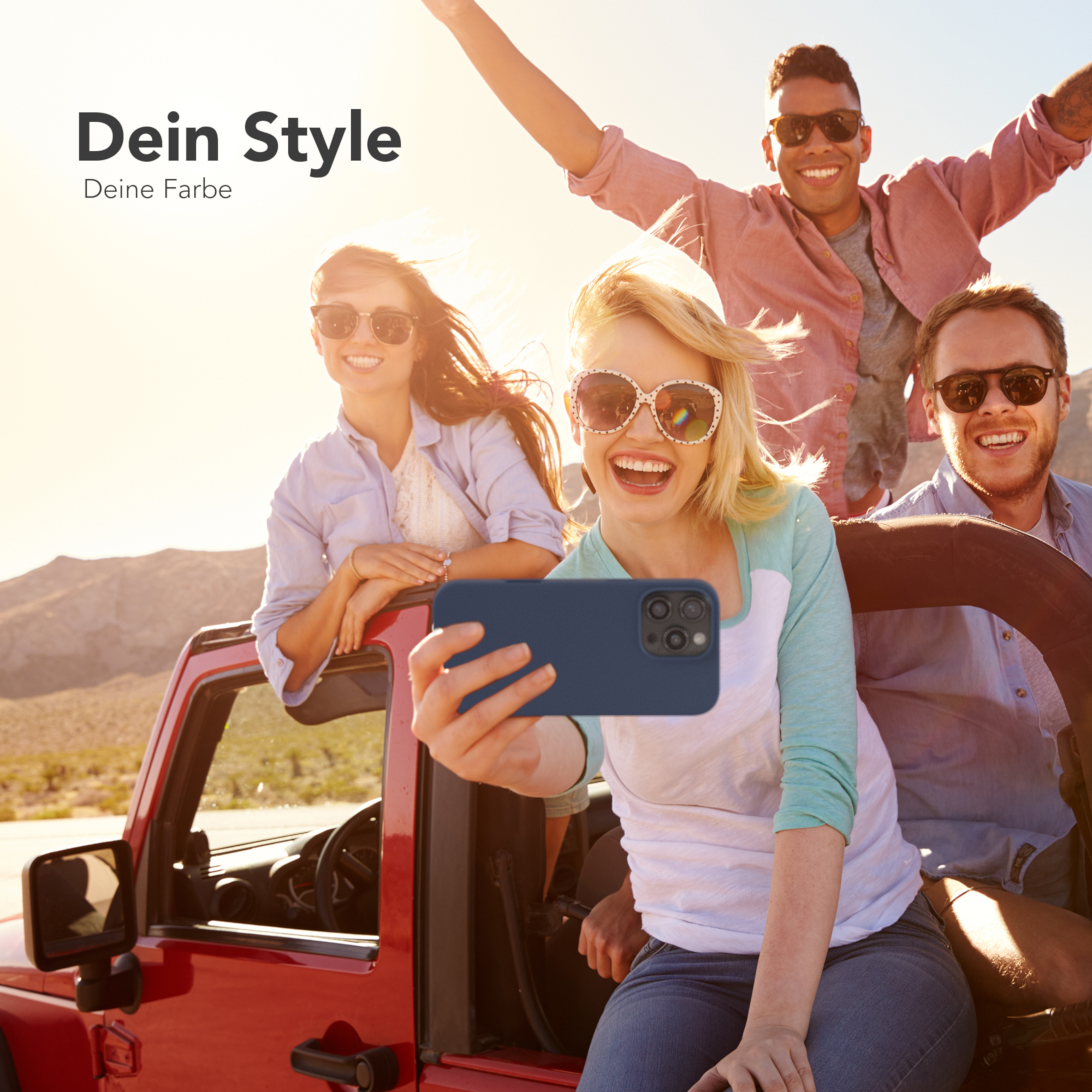 Vier Personen machen ein Selfie mit einem Telefon. Eine Person hält das Telefon in einem roten Jeep.