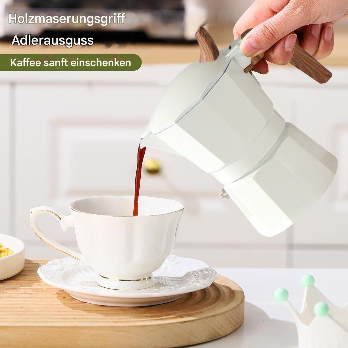 Eine weiße Kaffeekanne gießt Kaffee in eine weiße Tasse auf einer Untertasse. Holzgriff. Text: Holzmaserungsgriff.