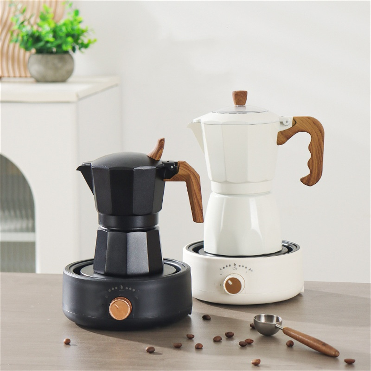 Zwei Kaffeemaschinen, schwarz und weiß, mit Holzgriffen, auf einem Tisch mit Kaffeebohnen und Löffel.