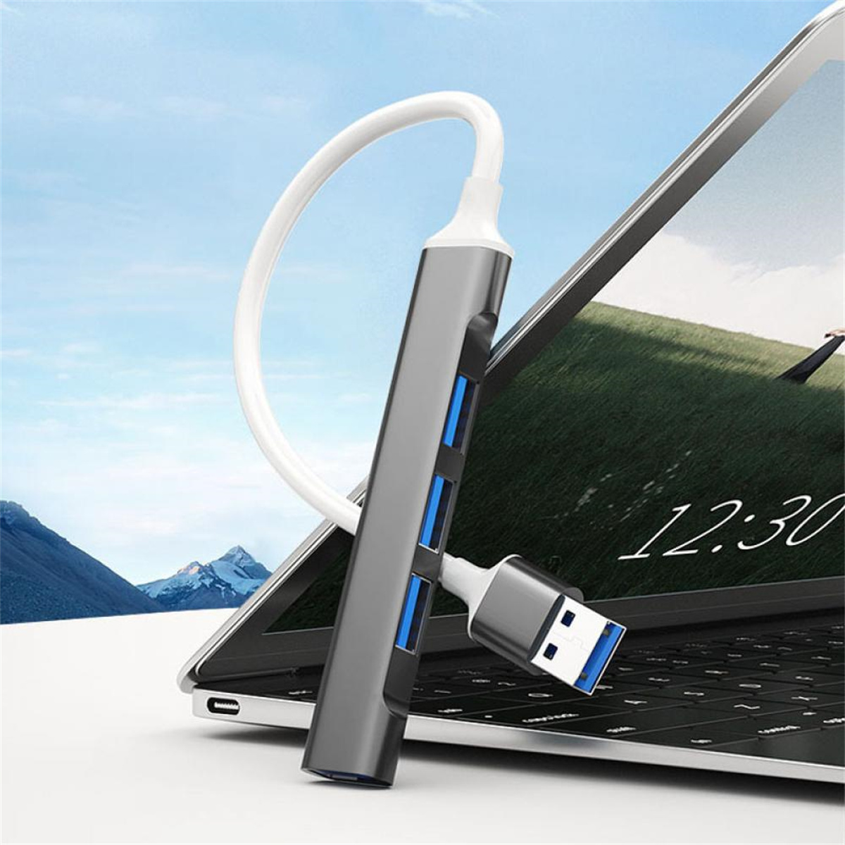 Ein USB-Hub, der mit einem Laptop verbunden ist. Der Hub ist silberfarben, mit USB-Anschlüssen und einem weißen Kabel.