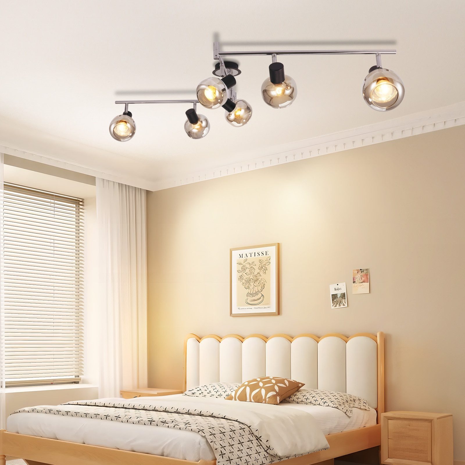 Sypialnia z reflektorami sufitowymi, łóżkiem i oprawioną sztuką.