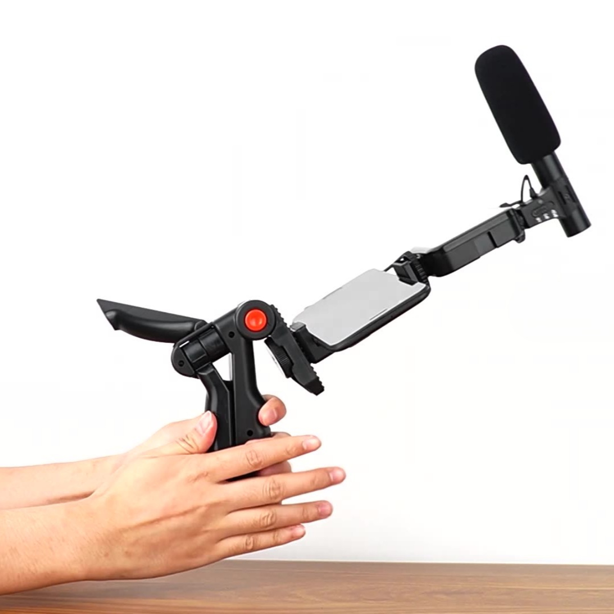 Hand hält ein schwarzes Videomikrofon und Stabilisator vor weißem Hintergrund.