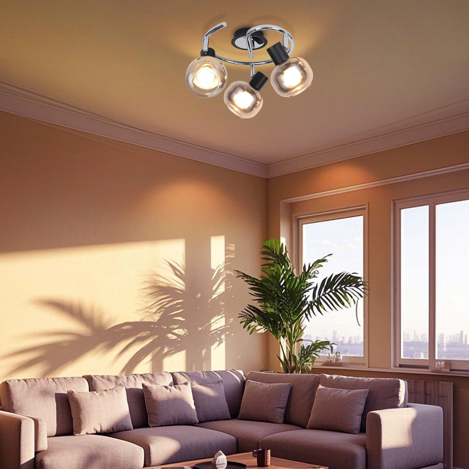 Oprawa oświetleniowa sufitowa z trzema szklanymi kulami. Oświetla salon z sofą i rośliną.