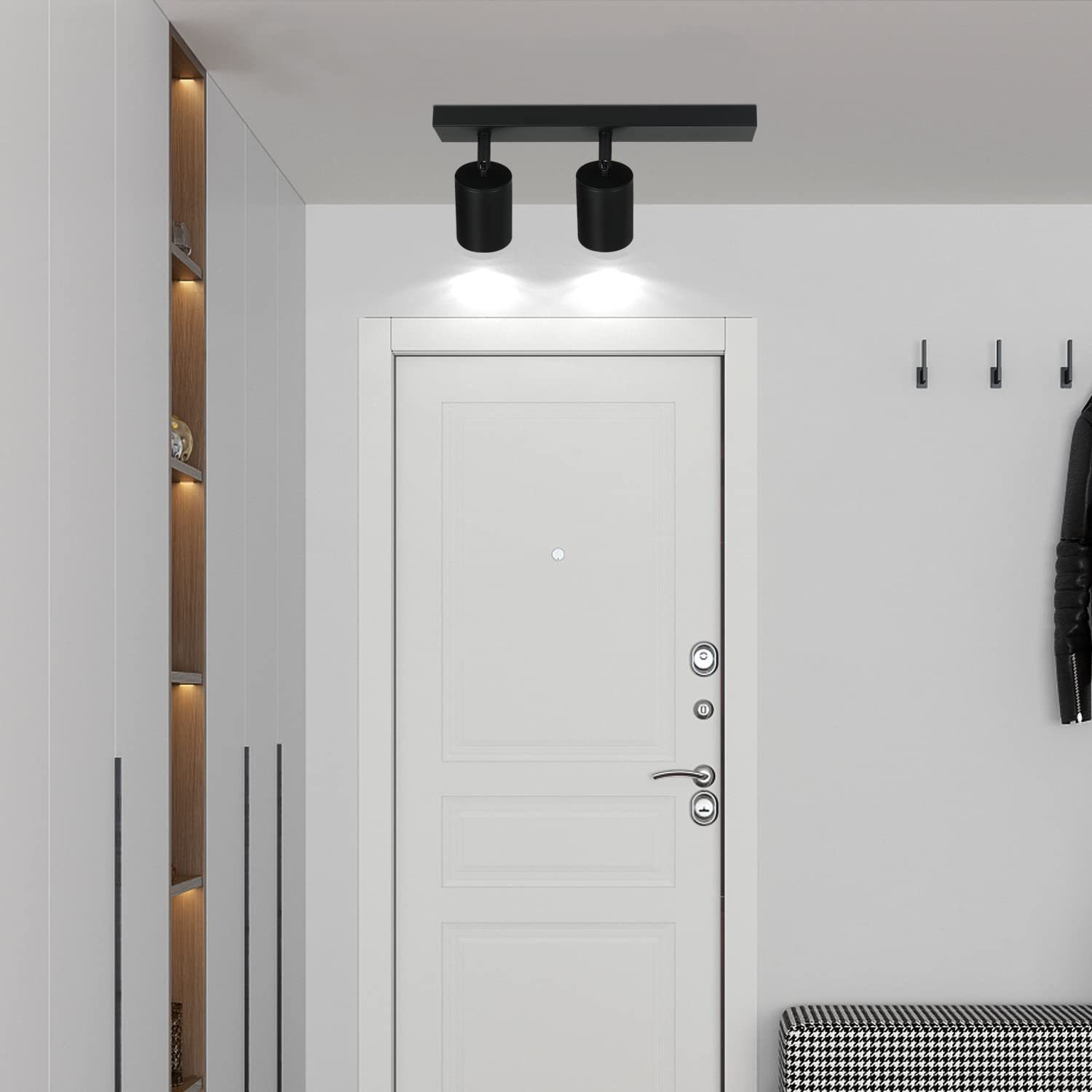 Nowoczesny korytarz z białymi drzwiami, dwoma czarnymi reflektorami na suficie i ławką.