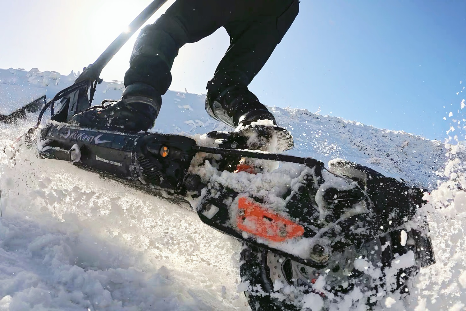 Persona su motoslitta nella neve, angolazione bassa, cielo blu.